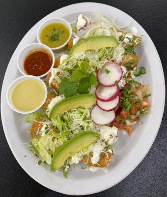A plate of food featuring sliced avocado, radishes, and a vibrant salsa.
