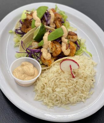 A plate of rice topped with shrimp and mixed vegetables, showcasing a colorful and appetizing meal.