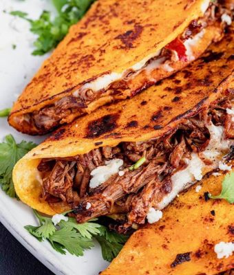 Mexican beef quesadillas served on a plate, filled with melted cheese and garnished with fresh cilantro.