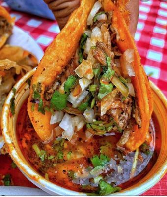A person holding a taco in their hand, showcasing the vibrant ingredients and tortilla.