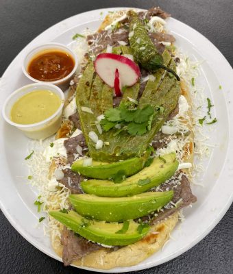 A plate featuring sliced meat, fresh avocado, and vibrant salsa arranged artfully.